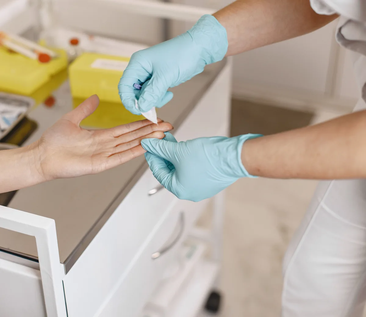Slaugytoja su medicininėmis pirštinėmis perriša paciento ranką
